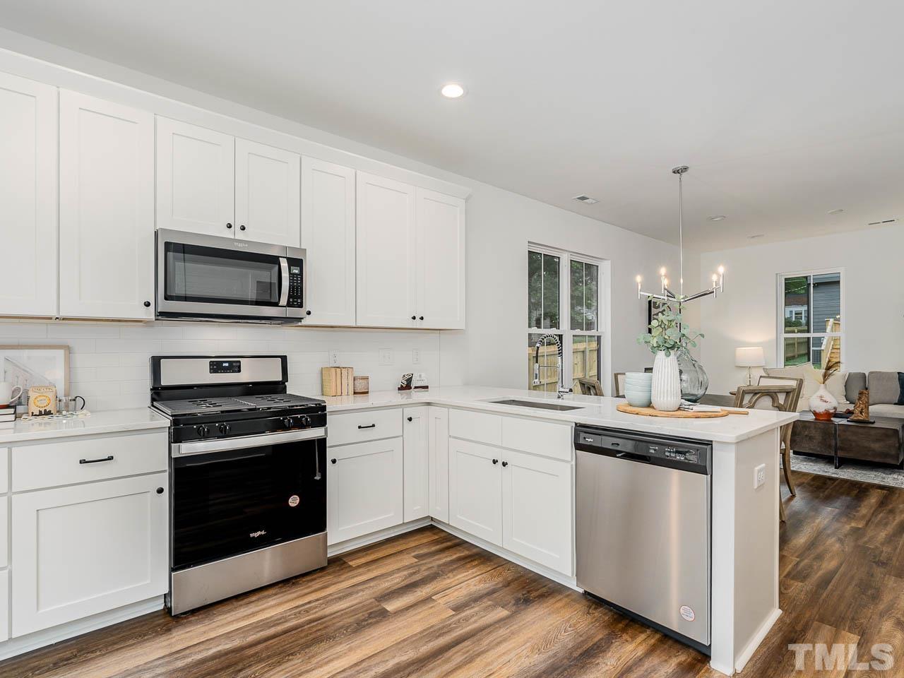 614 East Ellerbee Street Durham, NC 27704 - Photo 14 of 28 a kitchen with stainless steel appliances granite countertop a stove top oven a sink dishwasher and white cabinets with wooden floor