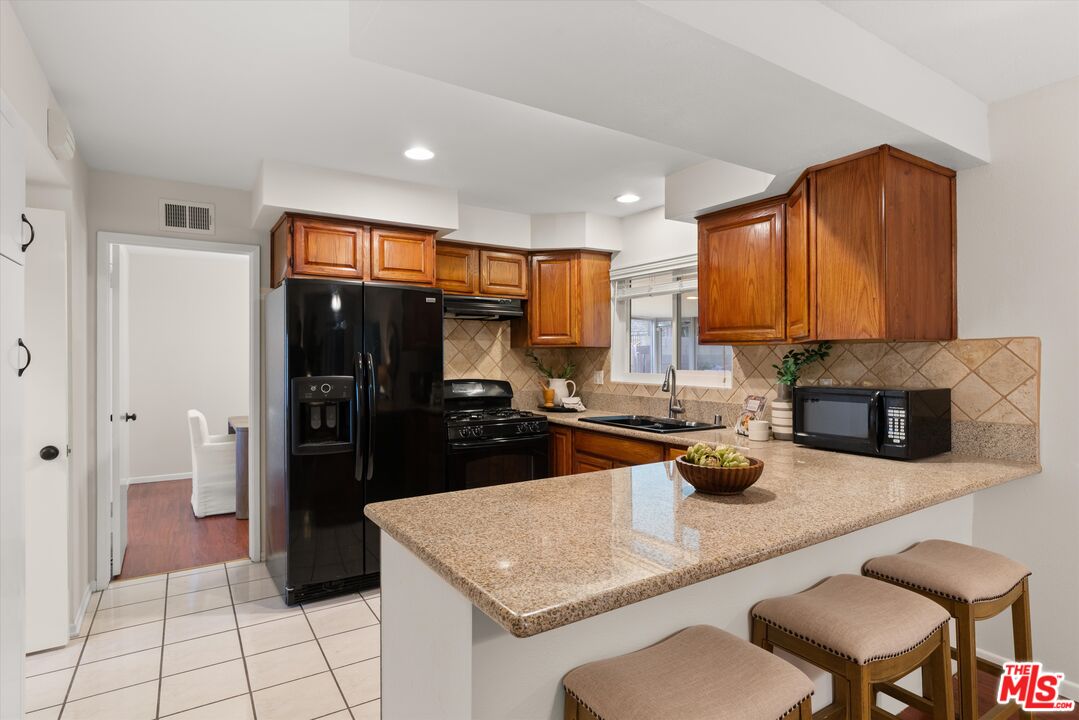 1407 East Kramer Drive Carson, CA 90746 - Photo 8 of 24 a kitchen with stainless steel appliances granite countertop a refrigerator and a stove top oven