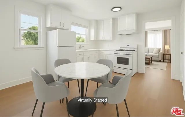 a kitchen with stainless steel appliances a dining table chairs and a refrigerator