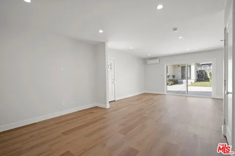 a view of an empty room with wooden floor and a fireplace