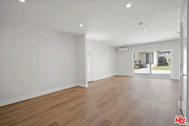 a view of an empty room with wooden floor and a fireplace