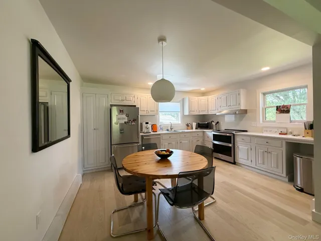a kitchen with stainless steel appliances kitchen island granite countertop a table chairs sink and cabinets