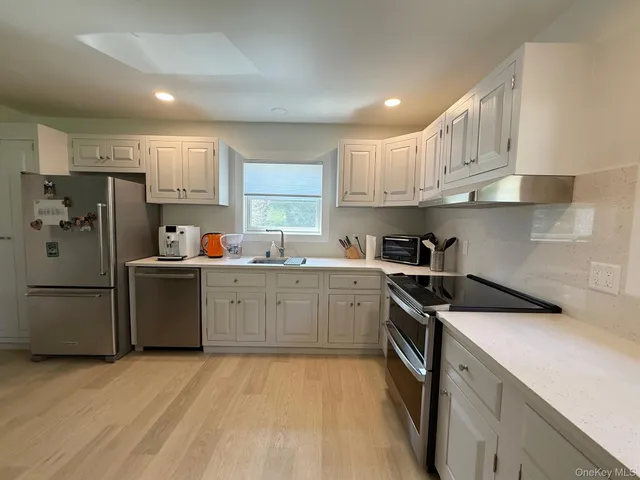 a kitchen with a sink a refrigerator and white cabinets