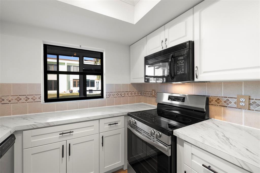 1 Windrush Boulevard, Unit 19 Indian Rocks Beach, FL 33785 - Photo 15 of 52 a kitchen with stainless steel appliances white cabinets granite counter tops and a window