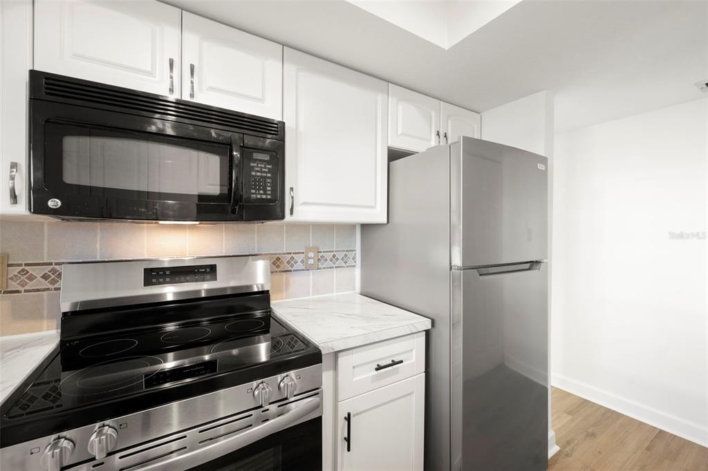 1 Windrush Boulevard, Unit 19 Indian Rocks Beach, FL 33785 - Photo 16 of 52 a kitchen with granite countertop cabinets and steel stainless steel appliances