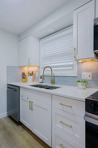 a kitchen with white cabinets and sink