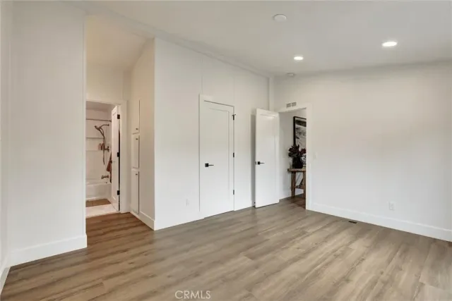 a view of an empty room with wooden floor and closet