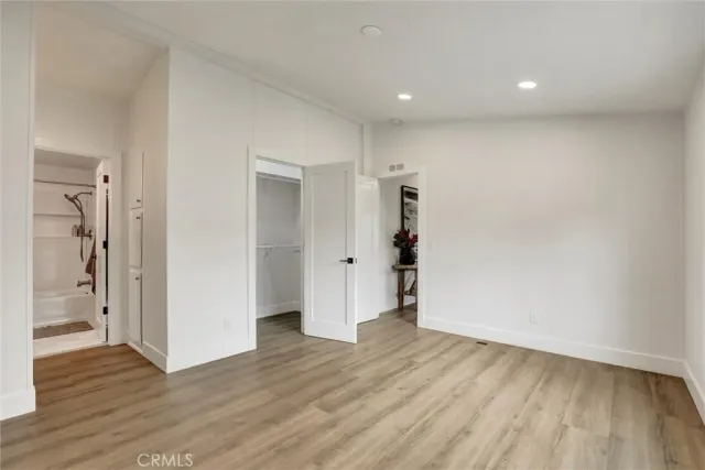 a view of an empty room with wooden floor and closet