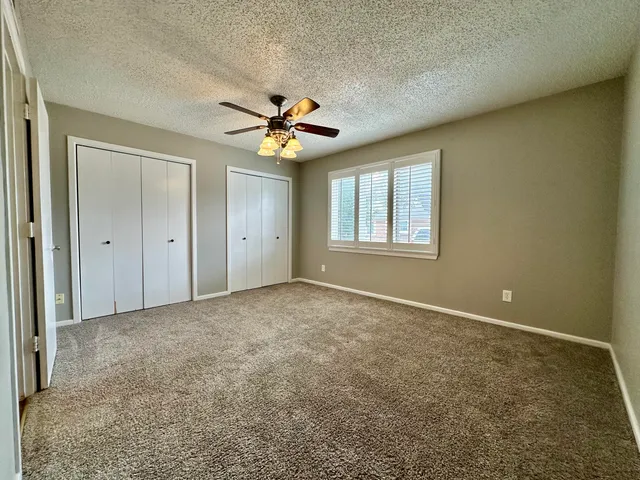 an empty room with windows and a chandelier fan