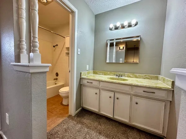 a spacious bathroom with a granite countertop sink a toilet and a mirror