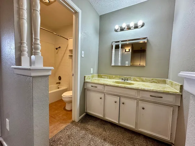 a spacious bathroom with a granite countertop sink a toilet and a mirror