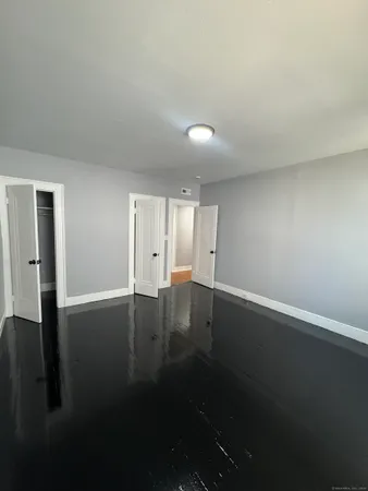 an empty room with wooden floor and windows with curtains