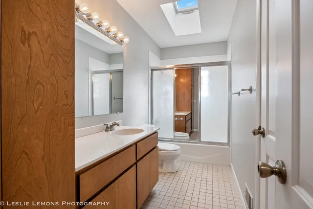 a bathroom with a sink a toilet a mirror and shower