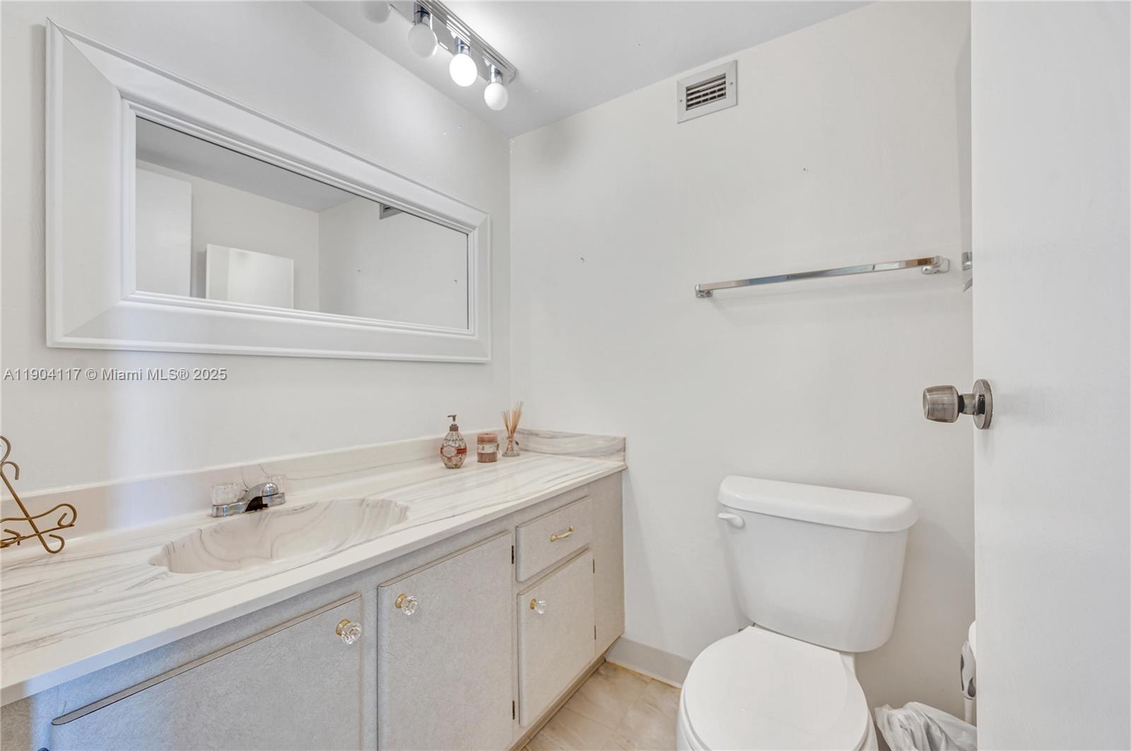 4101 Pine Tree Drive, Unit 707 Miami Beach, FL 33140 - Photo 10 of 41 a bathroom with a toilet sink vanity granite and mirror