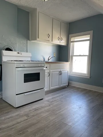 a kitchen with a stove top oven and white cabinets