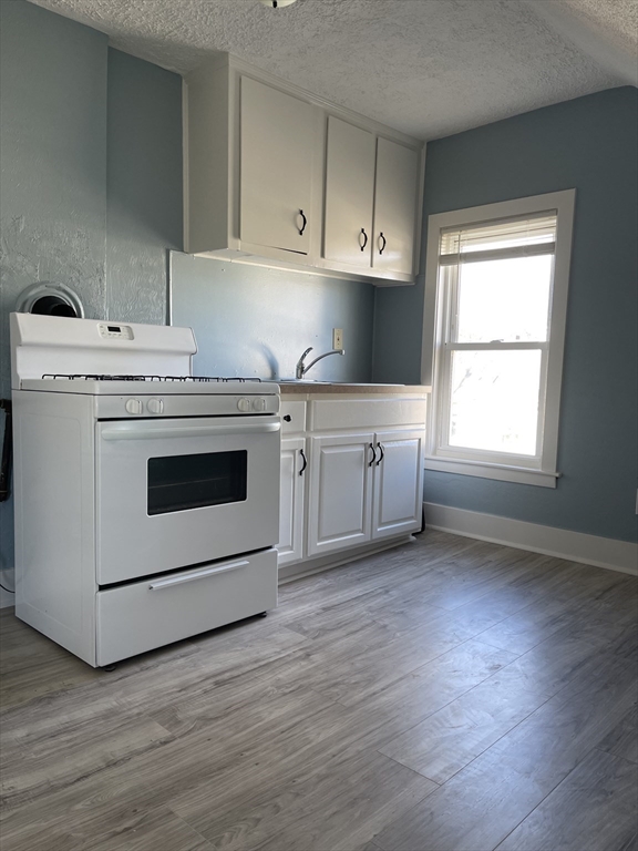 24 Union Street, Unit 3 Taunton, MA 02780 - Photo 1 of 10 a kitchen with a stove top oven and white cabinets