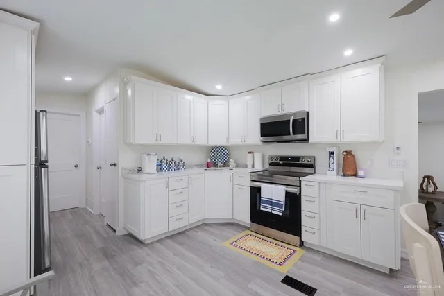 a kitchen with white cabinets stainless steel appliances and wooden floor