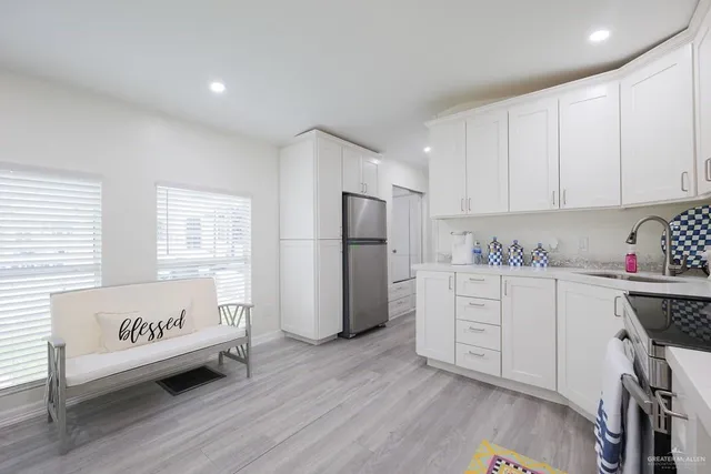a kitchen with stainless steel appliances granite countertop a refrigerator sink and white cabinets
