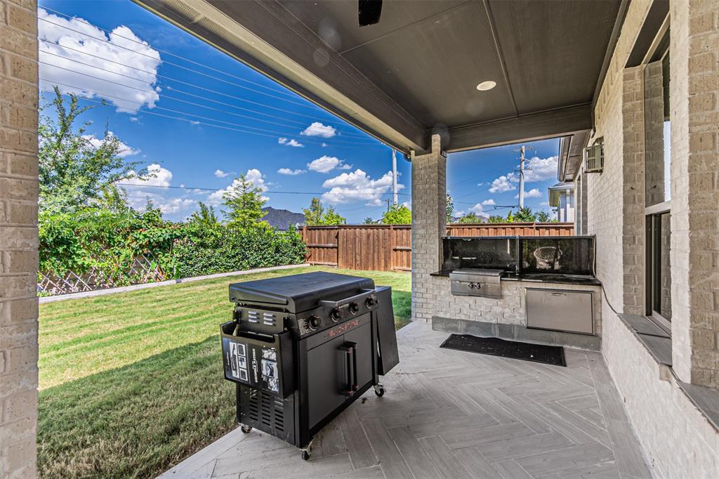 1070 Adair Road Prosper, TX 75078 - Photo 33 of 40 Covered outdoor patio featuring light brick columns, a dark ceiling with recessed lighting, and a built-in outdoor kitchen with a grill and stainless steel refrigerator