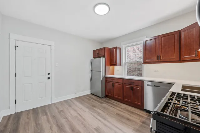 a kitchen with stainless steel appliances granite countertop a stove a sink dishwasher and a refrigerator with wooden cabinets