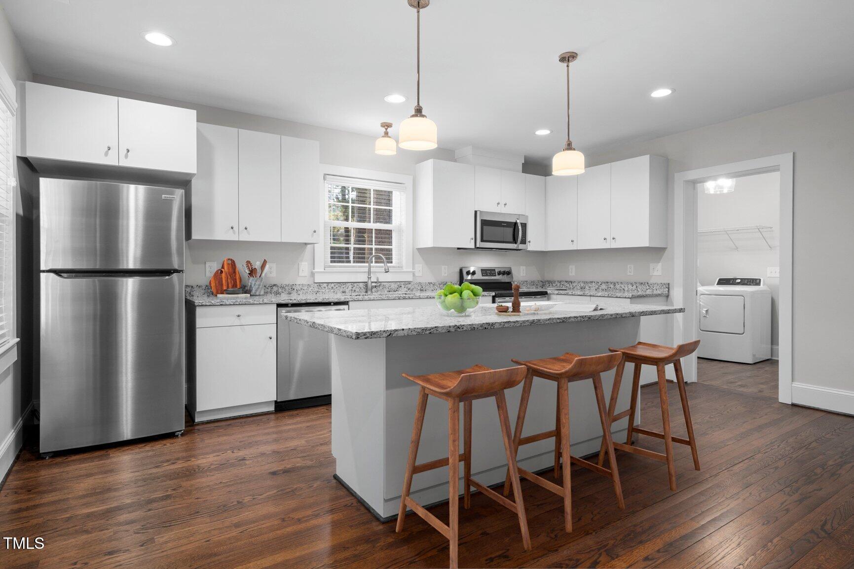 419 West Burnette Avenue Enfield, NC 27823 - Photo 7 of 23 a kitchen with stainless steel appliances granite countertop a refrigerator a sink a stove a dining table and chairs with wooden floor