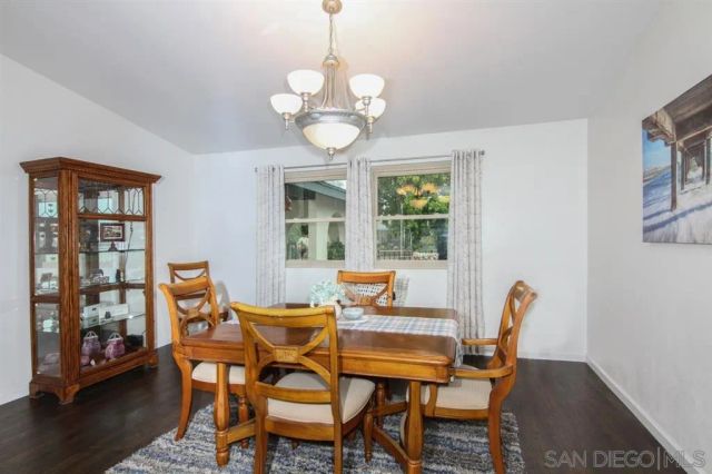 a dining room with wooden floor a chandelier a glass table and chairs