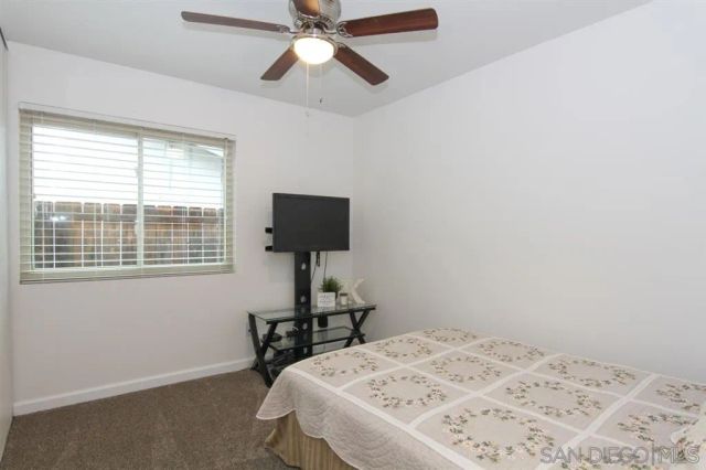 a bedroom with a bed and a flat tv screen on the dresser