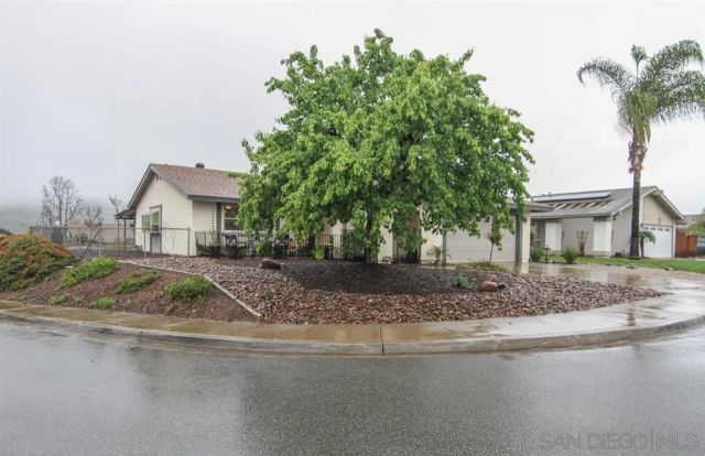 a view of house with a tree and wooden fence