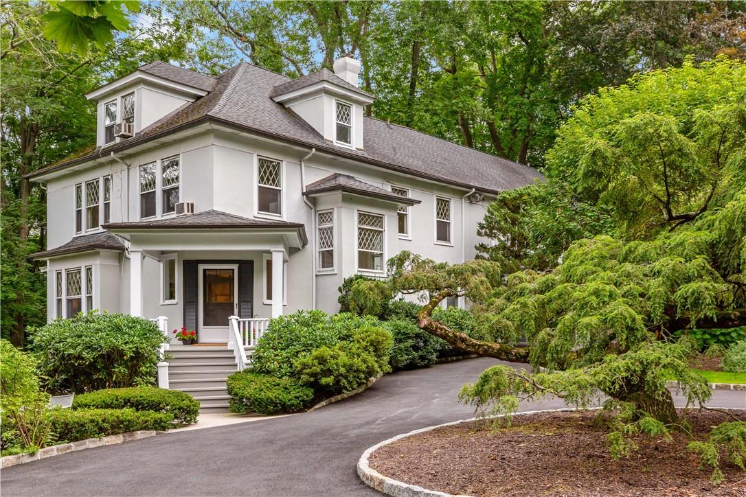 a view of a white house with large windows and plants