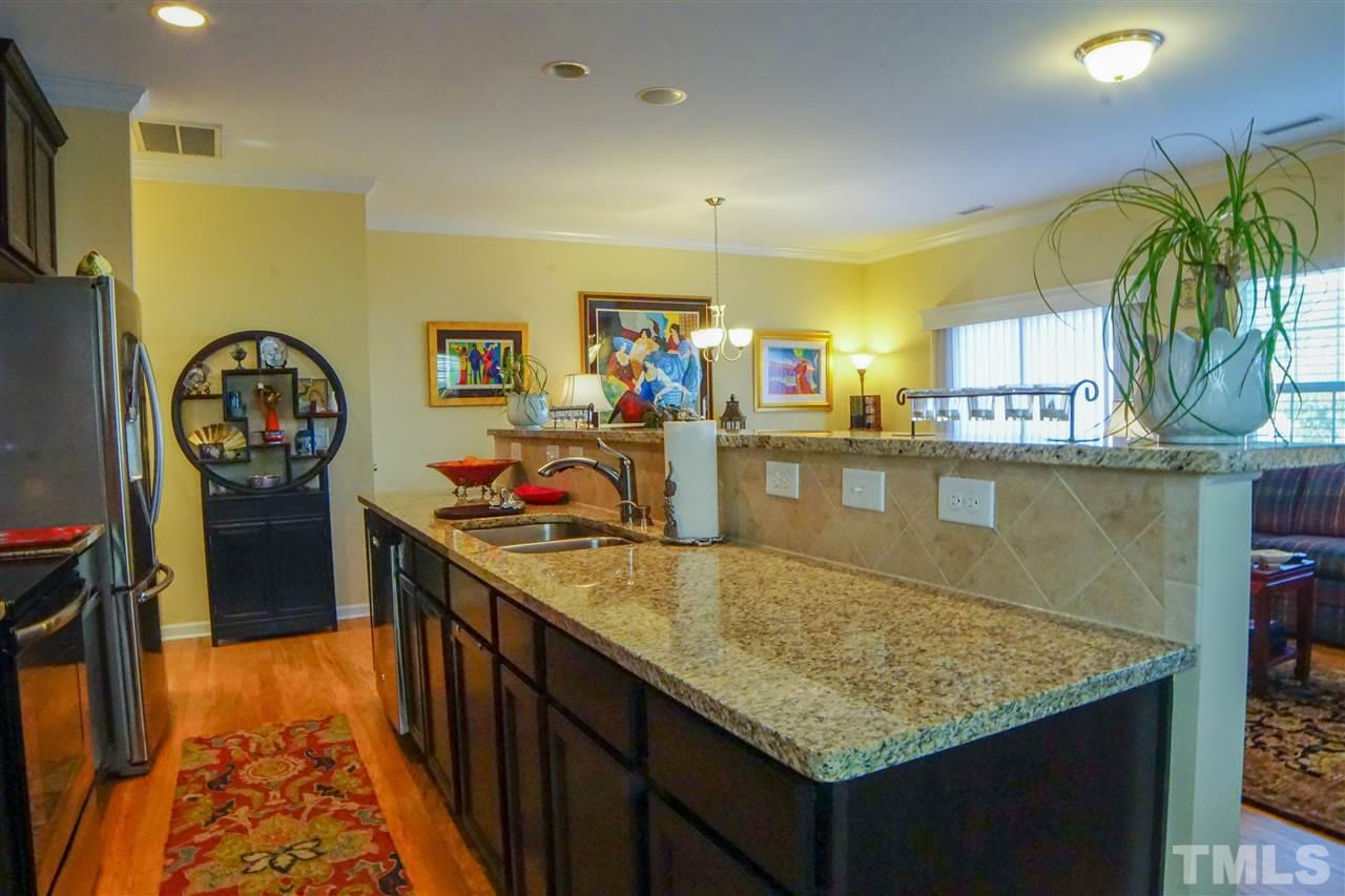 1023 Ileagnes Road Raleigh, NC 27603 - Photo 3 of 25 a kitchen with kitchen island granite countertop a table chairs in it and wooden floors