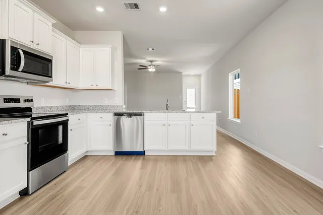 a kitchen with stainless steel appliances a white stove top oven cabinets and a wooden floor