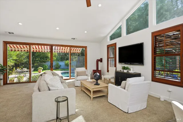 a living room with furniture a flat screen tv and a floor to ceiling window