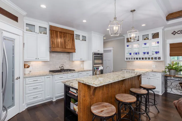 a kitchen with stainless steel appliances granite countertop a sink a stove a refrigerator and island