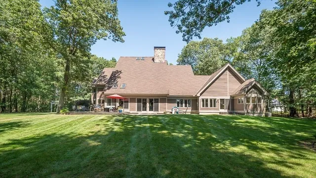 a view of a house with a big yard and large trees