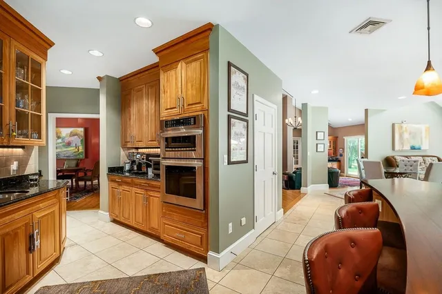 a living room with stainless steel appliances furniture a flat screen tv and kitchen view