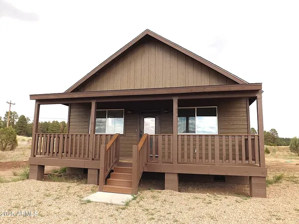 a view of wooden house with a small yard and wooden fence