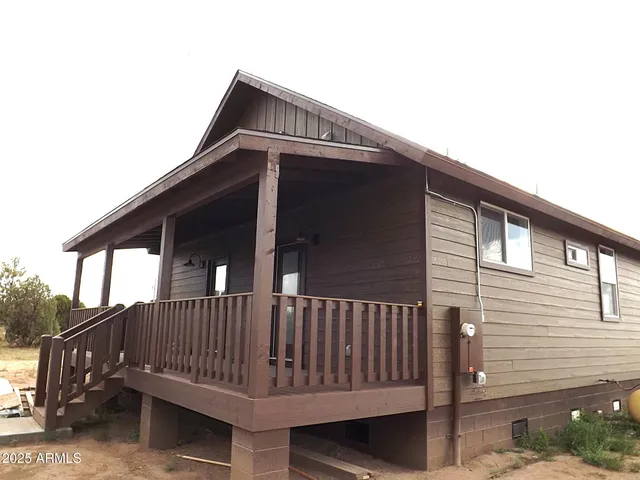 a view of wooden house with a small deck
