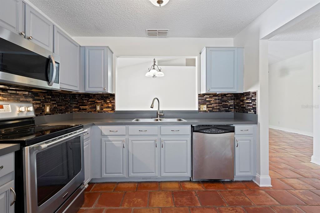 1533 Sunset View Circle Apopka, FL 32703 - Photo 12 of 23 a kitchen with stainless steel appliances a stove a sink and a microwave