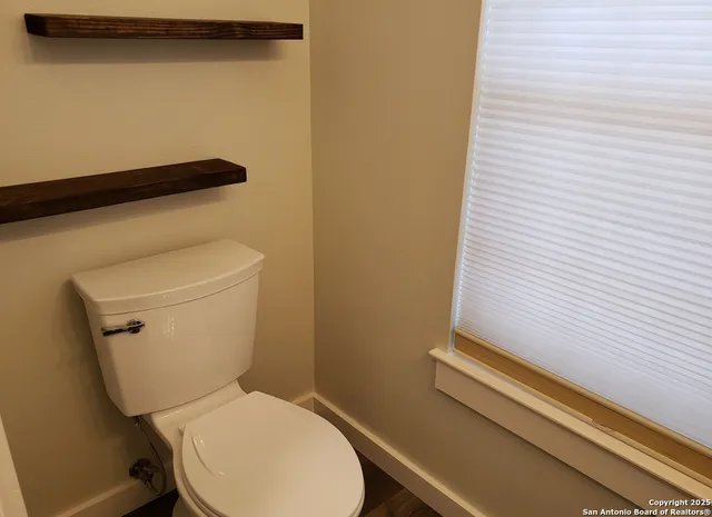 a white toilet sitting next to a white wall