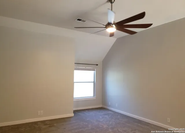 an empty room with windows and fan