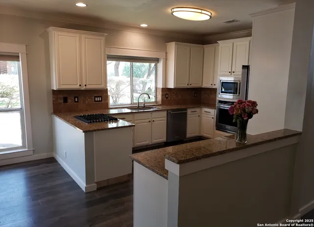 a kitchen with granite countertop wooden cabinets and a wooden floor