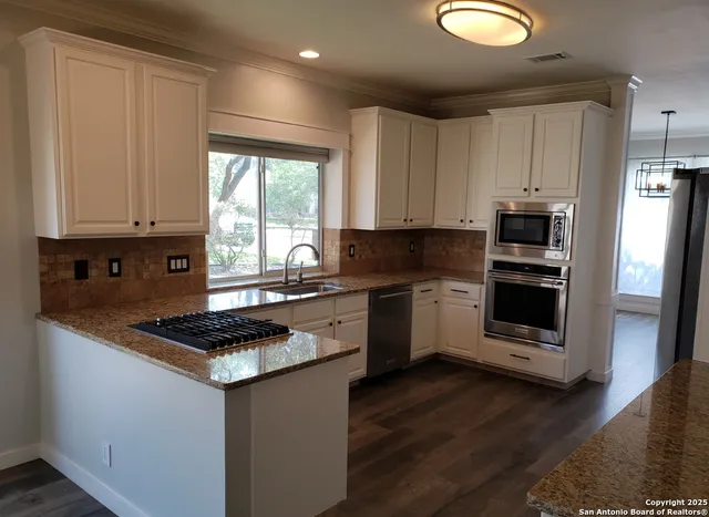 a kitchen with stainless steel appliances granite countertop a stove a microwave and a hard wood floor