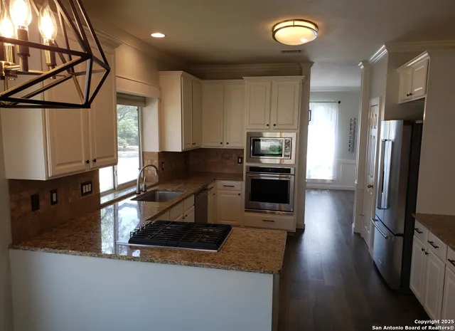 a kitchen with granite countertop stainless steel appliances a sink stove and refrigerator