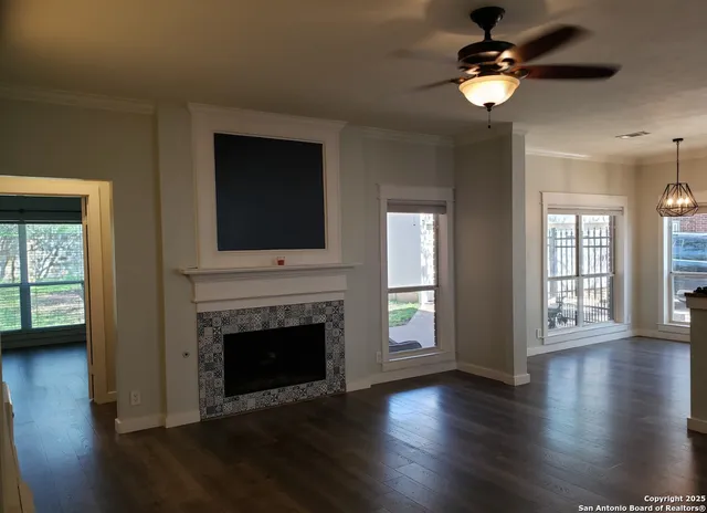 a view of an empty room with wooden floor fireplace and a window