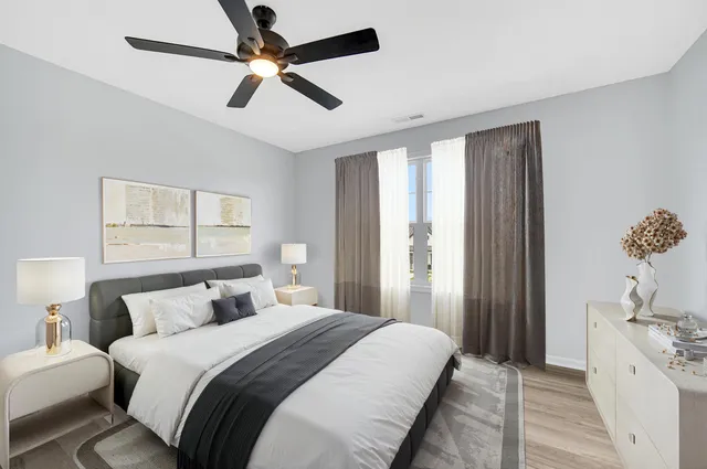 a bedroom with a large bed and a chandelier fan