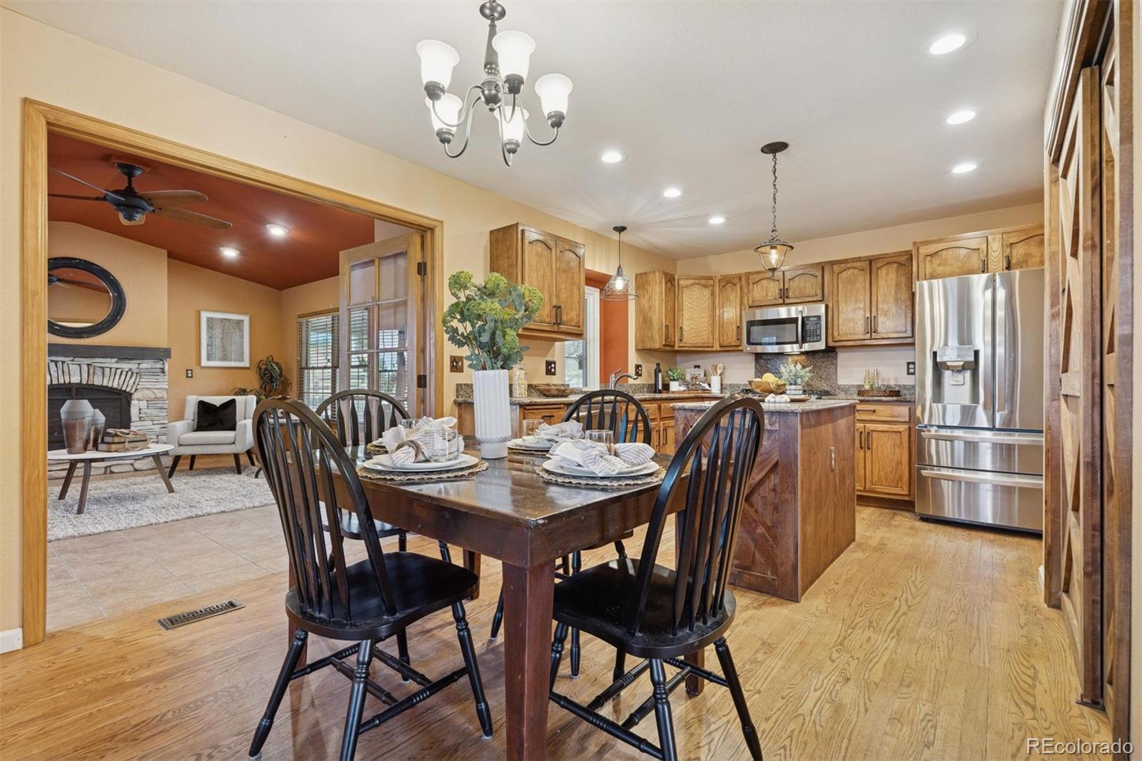 3779 Pasture Gate Circle Elizabeth, CO 80107 - Photo 23 of 49 a kitchen with stainless steel appliances kitchen island granite countertop a dining table chairs and refrigerator