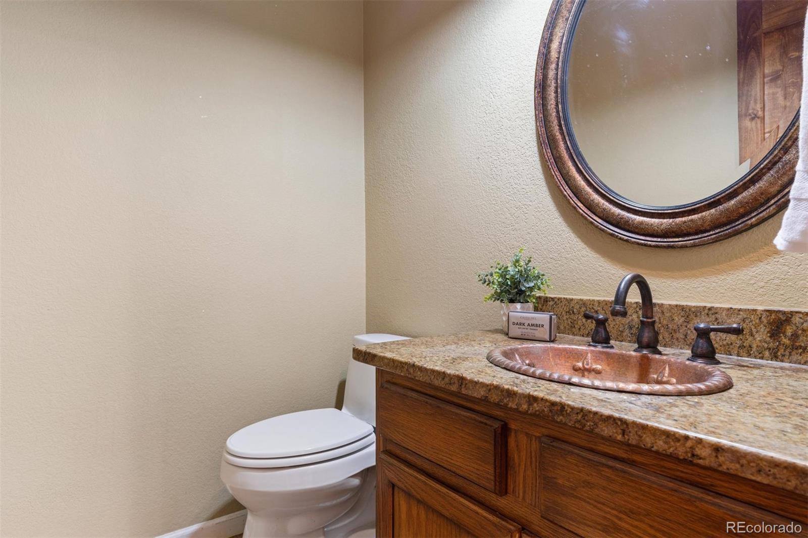 3779 Pasture Gate Circle Elizabeth, CO 80107 - Photo 32 of 49 a bathroom with a granite countertop toilet a sink and a mirror