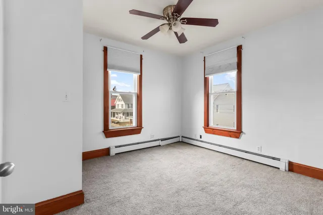 an empty room with windows and fan