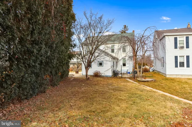 a view of a white house with a big yard and large tree