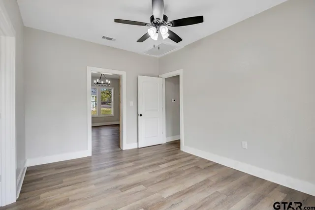 an empty room with wooden floor and ceiling fan